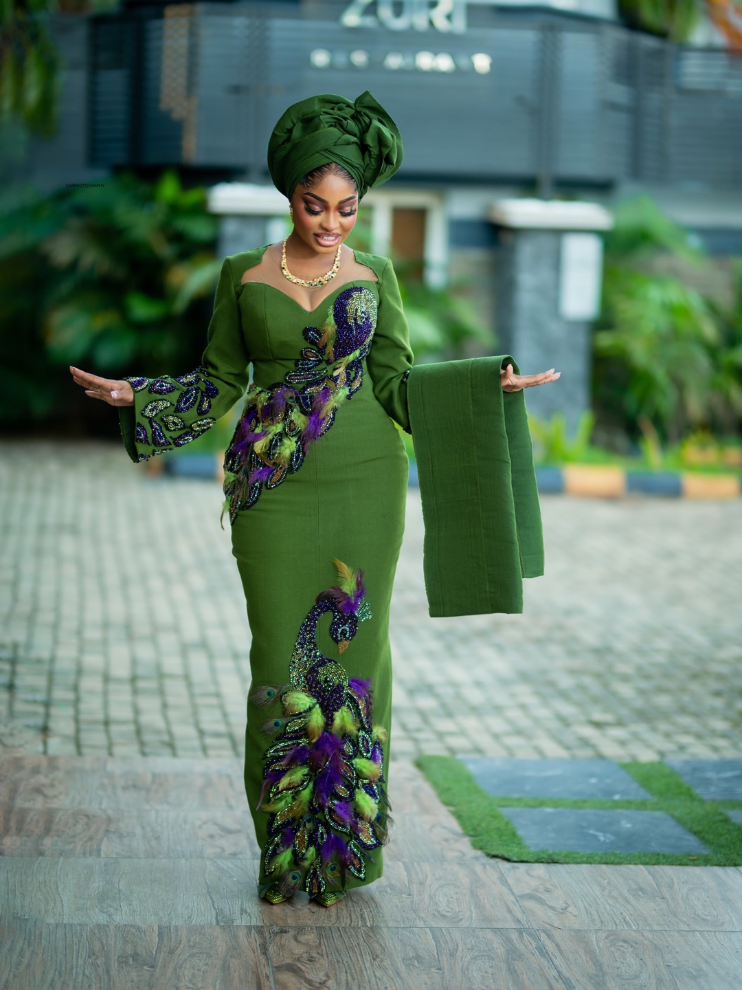 Green embroidered occasion dress with purple floral detailing and a matching gele
