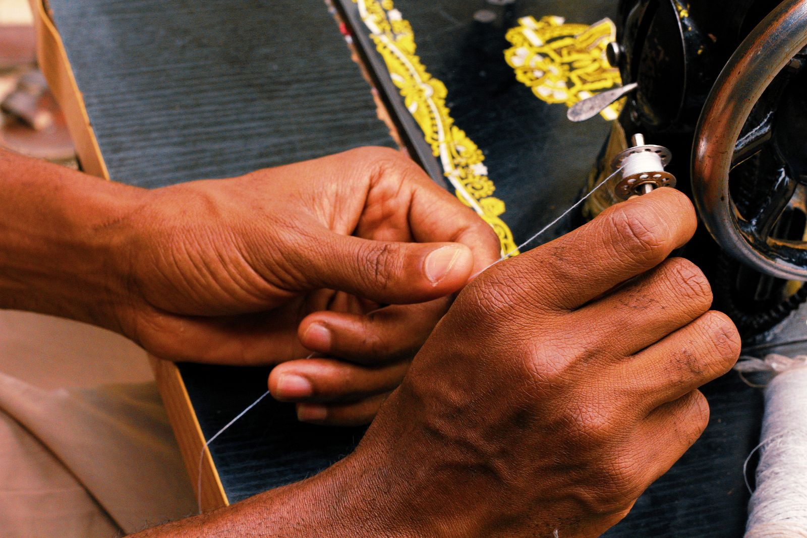 Hands threading a sewing machine in Abuja, Nigeria